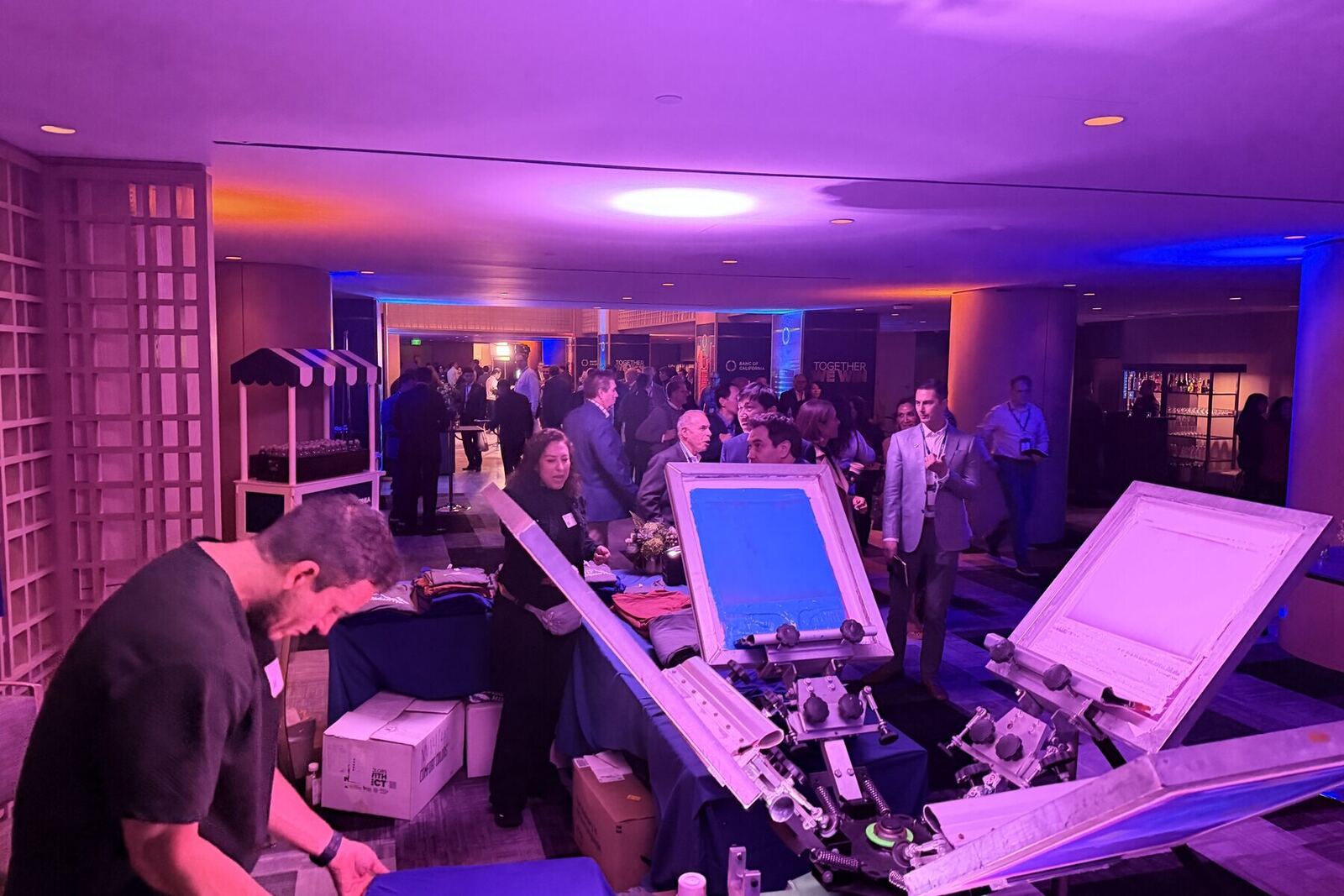 Evening sip-and-print party with guests gathered around a glowing live printing station